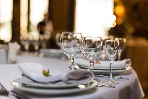 Beautiful table setting with crockery and flowers for a party, wedding reception or other festive event. Glassware and cutlery for catered event dinner. photo