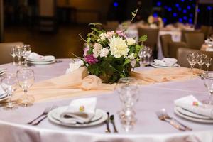 Beautiful table setting with crockery and flowers for a party, wedding reception or other festive event. Glassware and cutlery for catered event dinner. photo