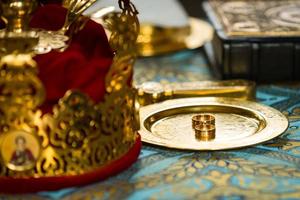 golden wedding rings on metal plate in church with holy water. wedding traditional ceremony. space for text photo