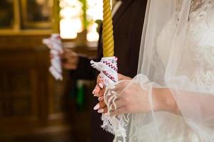 gorgeous bride and stylish groom holding candles at official wedding ceremony in old church. traditional moment photo