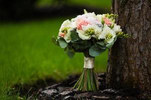 luxurious bridal bouquet of white peonies and roses near the tree photo