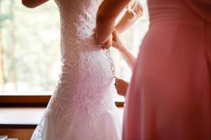 bridesmaid tying bow on wedding dress photo