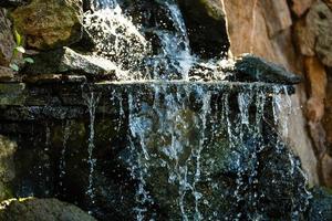 Cerca de salpicaduras de agua sobre las rocas de una cascada de agua sobre piedras decorativas foto