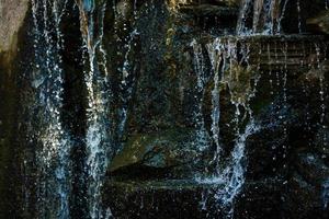 Cerca de salpicaduras de agua sobre las rocas de una cascada de agua sobre piedras decorativas foto