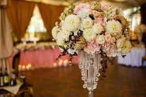 High vase with crystal chains and beig roses stands in the restaurant photo