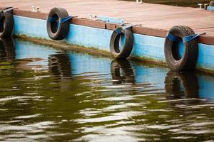 Row of black car tires used as boat bumpers photo