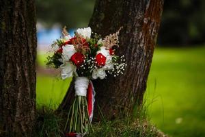 Beautiful bouquet of roses standing near a tree on the green grass photo