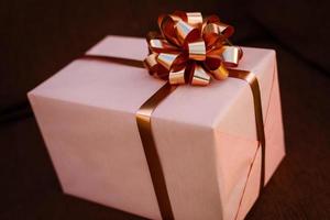 Handmade pink gift box with blue ribbon and bow on the wood old table. photo