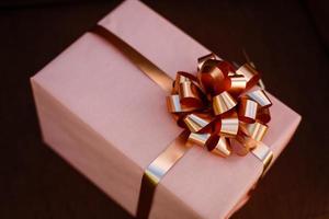 Handmade pink gift box with blue ribbon and bow on the wood old table. photo