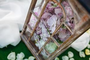 decoración de boda en estilo rústico. dos lámparas vintage blancas con flores en el interior de pie sobre hierba verde foto