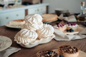 White airy meringue cake on the festive table, in the kitchen. photo