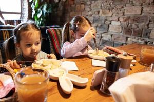 Family having a meal together in authentic ukrainian restaurant. Girls children eat dumplings. photo