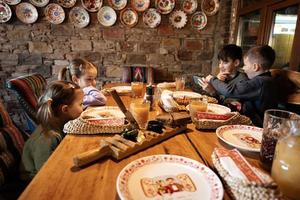 Four kids sit in authentic ukrainian restaurant, looking on phones. photo