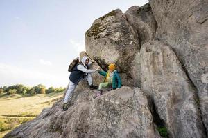 Father with son climbing big stone in hill. Pidkamin, Ukraine. photo