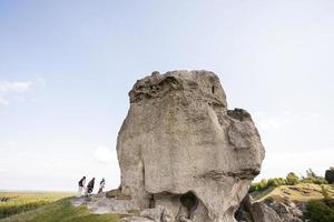 niños explorando la naturaleza. los niños usan mochilas de senderismo con la madre cerca de una gran piedra en la colina. pidkamin, ucrania. foto