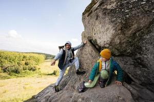 Father with son climbing big stone in hill. Pidkamin, Ukraine. photo