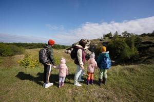 Activity on sunny autumn day, kids exploring nature. Children wear backpack hiking with mother. photo