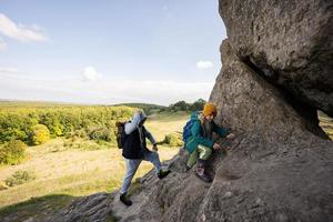 Father with son climbing big stone in hill. Pidkamin, Ukraine. photo