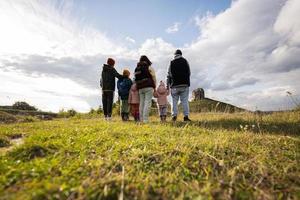 Family exploring nature. Back of children with parents stand against big stone in hill. Pidkamin, Ukraine. photo