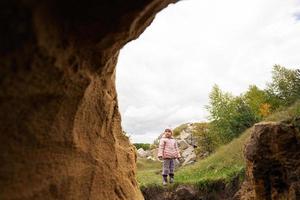 Baby girl explore limestone stone cave at mountain. photo