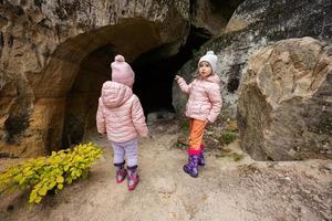 dos niñas exploran la cueva de piedra caliza en la montaña en pidkamin, ucrania. foto