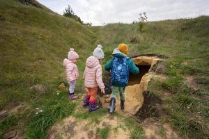 Three kids explore limestone stone cave at mountain. photo