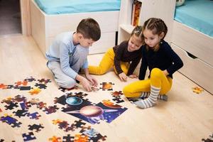 Children connecting jigsaw puzzle pieces in a kids room on floor at home.  Fun family activity leisure. photo