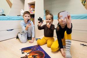 Children connecting jigsaw puzzle pieces in a kids room on floor at home.  Fun family activity leisure. photo