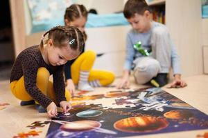 Children connecting jigsaw puzzle pieces in a kids room on floor at home.  Fun family activity leisure. photo