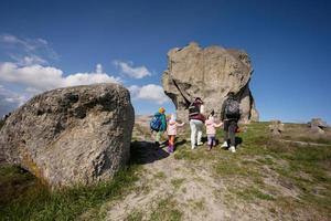 Kids exploring nature. Children wear backpack hiking with mother near big stone in hill. Pidkamin, Ukraine. photo