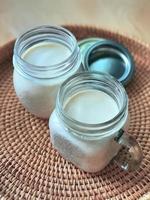 2 Two glasses of mason jars with natural homemade plain yoghurt, yogurt, on the handwoven rattan tray, wicker basket, high angle view. Soft theme color Korean cafe style, vertical photo