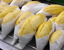 primer plano rollo de color amarillo dorado de carne durian envuelto en papel blanco, listo para comer, para la venta, sabor dulce, forma y forma natural, fruta tropical de temporada, rey de la fruta, tailandia foto