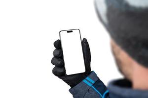 maqueta de teléfono de invierno en mano de hombre con chaqueta, guantes y sombrero. pantalla aislada y fondo para la presentación de la aplicación foto