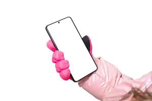 teléfono sostenido en una mano de niña enguantada de invierno, pantalla aislada y fondo para la promoción de la aplicación foto