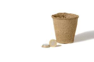 Coin and a peat pot for seedlings lying together, in a rural agricultural production company isolated over white. photo