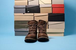 Stylish boots on the background of stacked shoe boxes. Shopping concept. Copy space. photo