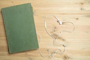 Book and headphones on a wooden table. Audiobook concept. Flatley. Copy space. photo