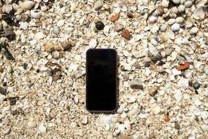 el teléfono inteligente se encuentra en conchas en la orilla del mar, se ha perdido. plano copie el espacio. foto