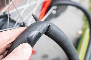 neumático de goma para bicicleta con un parche, reparado después de un pinchazo, en manos de un ciclista. foto
