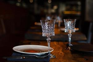 Glasses, forks, knives, plates on a table in restaurant served for dinner photo