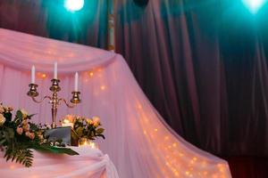 candelabro antiguo con ramo de boda. candelabro de boda con decoración floral antes de la ceremonia de boda. mesas preparadas para una recepción de boda foto