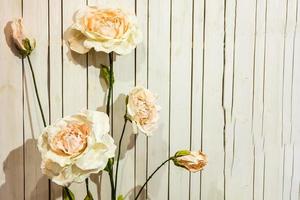 White artificial roses in vase on old white vintage wooden background photo