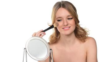 beautiful blond young smiling woman apply makeup with brush. isolated photo