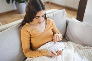 woman using cotton swab while doing coronavirus PCR test at home. Woman using coronavirus rapid diagnostic test. Young woman at home using a nasal swab for COVID-19. photo