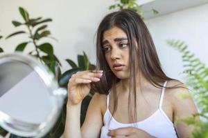 Woman looking at damaged splitting ends of hair. Woman hand holding her long hair with looking at damaged splitting ends of hair care problems photo