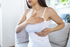 Young caucasian woman palpating her breast by herself that she concern about breast cancer. Healthcare and breast cancer concept photo