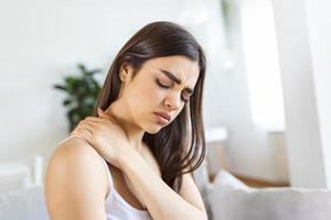 mujer cansada masajeando el cuello rígido y dolorido, músculos tensos fatigados por el trabajo de la computadora en una postura incorrecta mientras siente dolor en las articulaciones del hombro dolor de espalda. concepto de fibromialgia foto