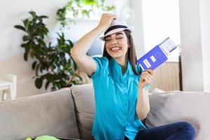 Woman is preparing for travel during covid-19 pandemic. Holding passport, ticket and negative coronavirus test in hand while suitcase is standing nearby. Summer travel and vacation concept photo