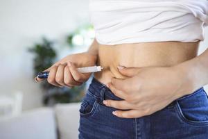 un paciente diabético que usa una pluma de insulina para inyectarse insulina en casa. mujer joven controlar la diabetes. estilo de vida diabético foto