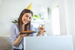 nuevo concepto normal. mujer feliz celebrando su cumpleaños sola. mujer joven sosteniendo un pastel. fiesta de cumpleaños en casa. videollamada familiar. distanciamiento social. vida en casa. foto